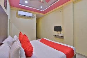 Schlafzimmer mit einem Bett mit roten Kissen und einem TV in der Unterkunft Hotel O D K Guest House in Anand