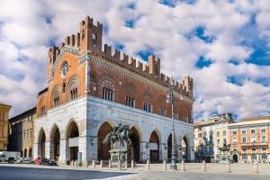 a large brick building with a clock tower at the central house piacenza in Piacenza