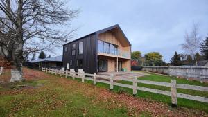 a black house with a wooden fence in front of it at Luxe on the Lake Front in Te Anau