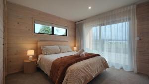 a bedroom with a large bed with a window at Luxe on the Lake Front in Te Anau