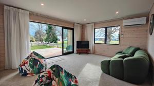 a living room with a green couch and a television at Luxe on the Lake Front in Te Anau