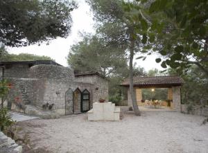 a stone house with a patio and a tree at Trullo in the Wood in Nardò