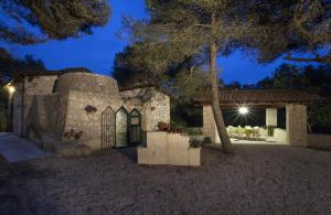 un antico edificio in pietra con un tavolo e un albero di Trullo in the Wood a Nardò