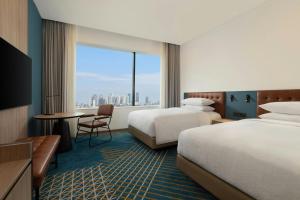 a hotel room with two beds and a large window at Four Points by Sheraton Jakarta Thamrin in Jakarta
