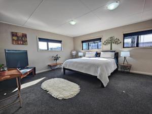 a bedroom with a bed and a flat screen tv at Korimako Sea View Sanctuary in Riverton