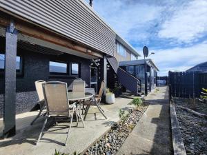 a patio with a table and chairs in front of a house at Korimako Sea View Sanctuary in Riverton