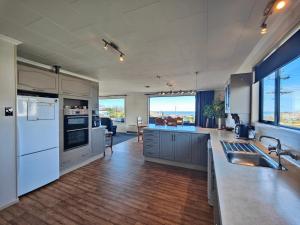 a large kitchen with white appliances and a large window at Korimako Sea View Sanctuary in Riverton