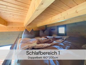 a large bed in a room with a wooden ceiling at TinyHousebeiDresden spektakuläres winziges Häuschen auf Stelzen im Pferdeteich, Kaminofen, umlaufende Terrasse - Nähe Sächsische Schweiz - Von Juni - September Mindestmietzeit 1 Woche Sa-Sa in Großharthau