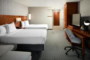 a hotel room with two beds and a desk and a television at Courtyard by Marriott Waldorf in Waldorf