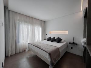 a white bedroom with a large bed and a window at chalé mantiqueira in Gonçalves +40 photos