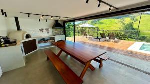 a living room with a wooden table and a large window at chalé mantiqueira in Gonçalves