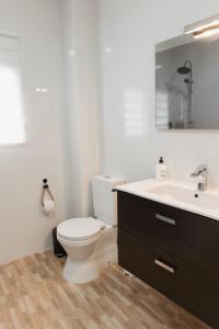 a white bathroom with a toilet and a sink at Casa Las niñas in La Algaba