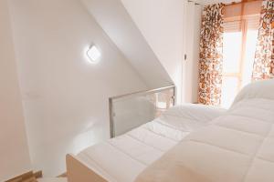 a white room with two beds and a window at Casa Las niñas in La Algaba