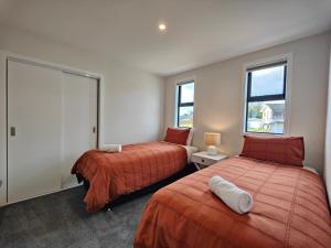 a bedroom with two beds and two windows at Luxury on Luxmore in Te Anau +21 photos