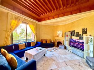 マラケシュにあるLes Jardins de la palmeraieの青いソファとテレビのあるリビングルーム