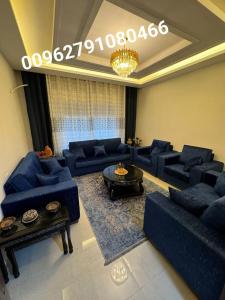 a living room with blue couches and a chandelier at طبربور in Amman