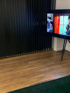 una televisione su un supporto in una stanza con tende nere di Posh 1 Bed Flat-Direct links to Central London a West Thurrock