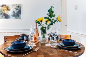 a wooden table with plates and glasses and a vase with yellow flowers at Cosy Sleeps 5 Bedford Stay Superfast WiFi in Bedford +23 photos