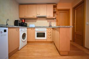 a kitchen with wooden cabinets and a washer and dryer at A 2 min de Grandvalira I Ski, Vistas, Wifi y Parking in Soldeu