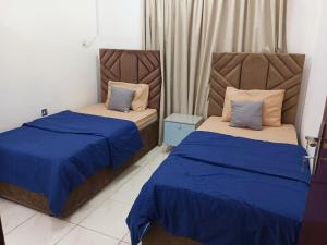 deux lits dans une chambre avec du bleu et du blanc dans l'établissement Luxury 2-Bedroom Apartment on Buhaira Corniche, à Charjah