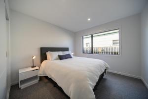 a white bedroom with a large bed and a window at Te Anau Lake Escape in Te Anau