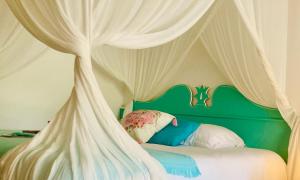a bed with a green canopy with white curtains at TIKAZADAPH, pour un séjour de charme, romantique & exotique, 97180 Sainte-Anne in Sainte-Anne +26 photos