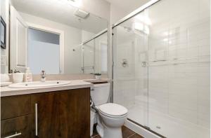 a bathroom with a toilet and a sink and a shower at The Spruce Modern 2BR Condo with Pool & Parking in Calgary