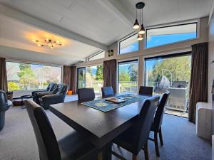 a dining room with a table and chairs and windows at View Over The Square in Te Anau