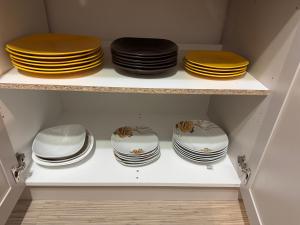 four plates and bowls on a shelf in a cabinet at Apartament Brazdă in Craiova