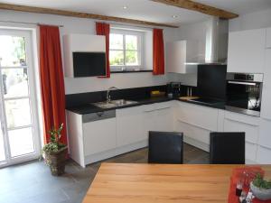 a kitchen with white cabinets and red curtains and a table at Chasa Vidos 270 - Familie Scandella in Sent