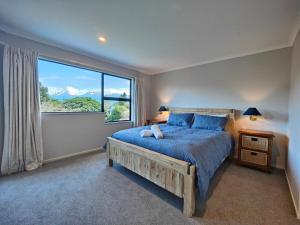 a bedroom with a large bed and a large window at Grand Getaway Te Anau in Te Anau