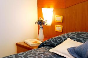 1 dormitorio con un jarrón con flores sobre una mesa en Hotel Ariston, en Marina di Grosseto