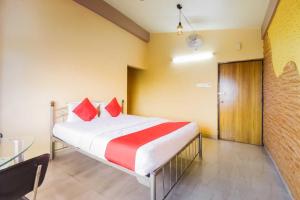 a bedroom with a bed with red pillows and a table at Hotel O Ritz Rivera in Kolkata