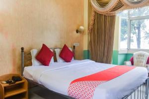 a bedroom with a bed with red pillows and a window at Hotel O Ritz Rivera in Kolkata