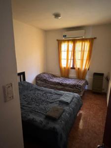 a bedroom with two beds and a window with curtains at desertico in Neuquén