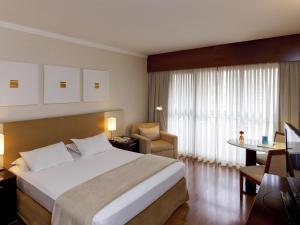 a hotel room with a large bed and a desk at Mercure Sao Paulo Grand Plaza Paulista in Sao Paulo