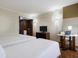 a hotel room with two beds and a desk with a laptop at Mercure Sao Paulo Grand Plaza Paulista in Sao Paulo +99 photos