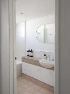 un bagno bianco con lavandino e specchio di Castaways Penthouse Noosa, Beachfront Pool Tennis a Castaways Beach