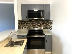 a kitchen with a stove and a sink and a microwave at Ramada by Wyndham Los Angeles/Wilshire Center in Los Angeles