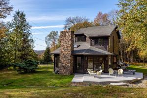 a large house with a stone chimney and chairs at Dreamwood in Jeffersonville