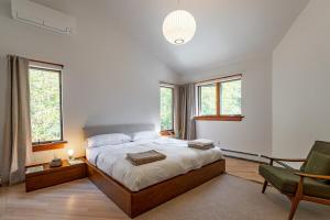 a bedroom with a bed and a chair and windows at Dreamwood in Jeffersonville