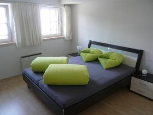 1 dormitorio con 1 cama con 2 almohadas verdes en Chasa Vidos 270 - Familie Scandella, en Sent