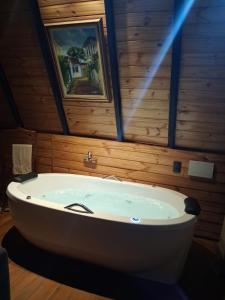 a large white bath tub in a room with wooden walls at Chalé Canto da Mata - Com Piscina e Café da Manhã in Sapucaí-Mirim