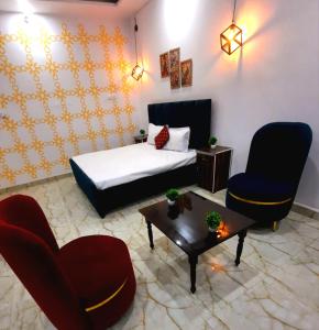 een kamer met een bed en twee stoelen en een tafel bij The Moksha Residency By MOM'S in Prayagraj