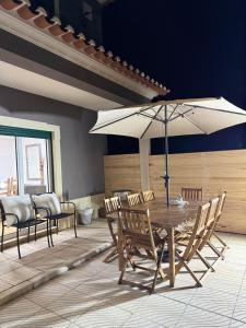 Una mesa y sillas con una sombrilla en un patio. en Mãos n'Areia, en Ferrel