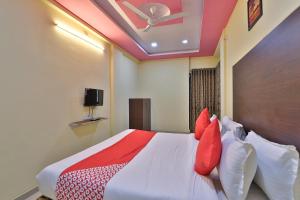Schlafzimmer mit einem Bett mit roten Kissen und einer Decke in der Unterkunft Hotel O D K Guest House in Anand + 23 Fotos