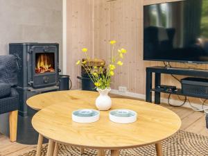 a wooden table with a vase of flowers and a fireplace at 4 person holiday home in Hjørring-By Traum in Lønstrup