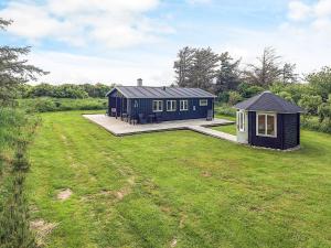 a black house in the middle of a grass field at 4 person holiday home in Hjørring-By Traum in Lønstrup