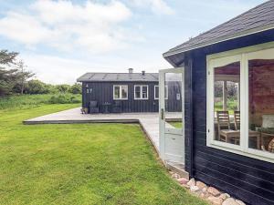 a black house with a patio and a yard at 4 person holiday home in Hjørring-By Traum in Lønstrup +16 photos