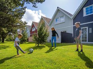 3 enfants jouant avec un ballon de football dans une cour dans l'établissement Type 10- Ho Holiday Centre holiday home, à Blåvand